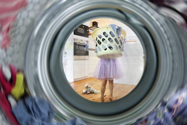 Girl carrying basket of clothes to washing machine