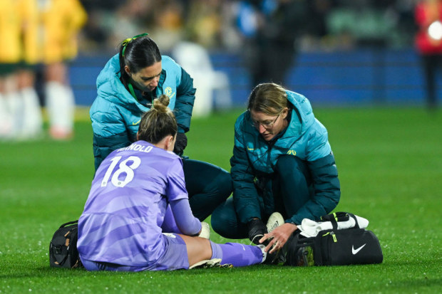 Mackenzie Arnold goalkeeper of Australia is helped by team medical staff.