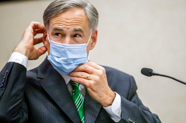  Texas Gov. Greg Abbott adjusts his mask.
