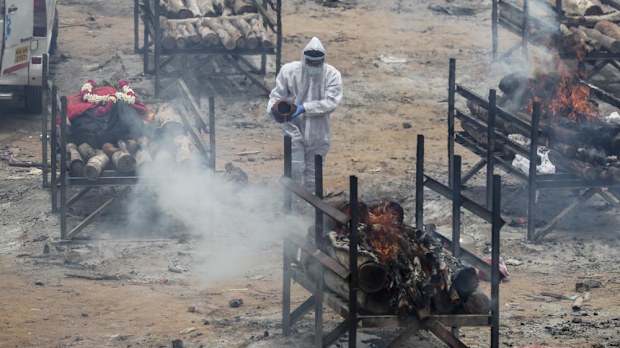 A man performs rituals as bodies of people who died of COVID-19 are cremated at an open crematorium on the outskirts of Bengaluru, Karnataka state, India. 