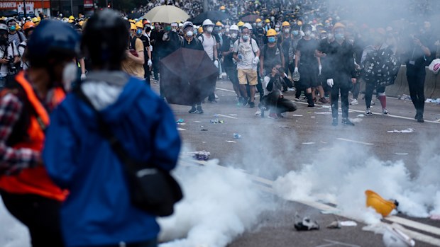 Protesters try to retreat through tear gas smoke canisters away from them during the demonstration.