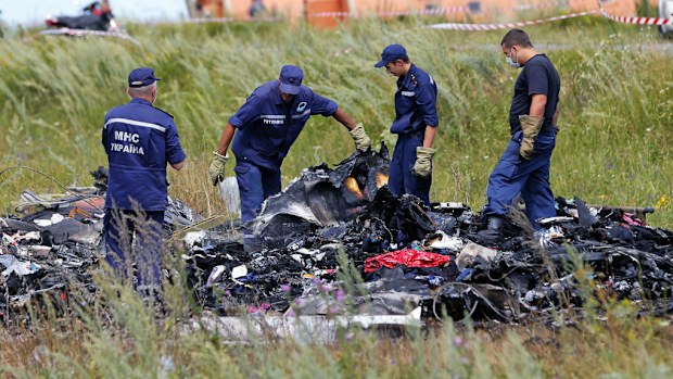 Ukrainian emergency workers inspect debris at the MH17 crash site. (AAP)