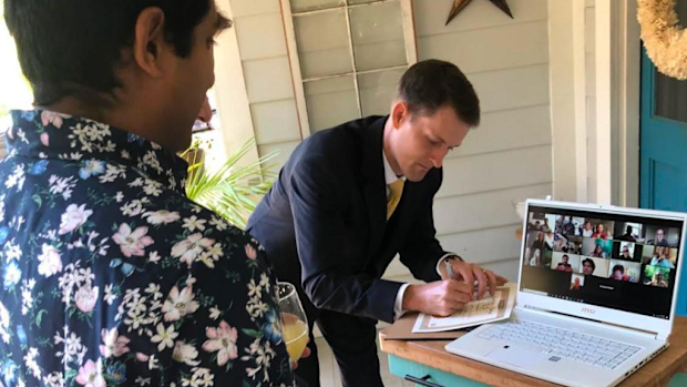 The happy couple signs their marriage certificate in front of their electronic witnesses.