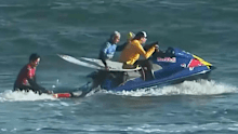 A surfer is helped out of the water.