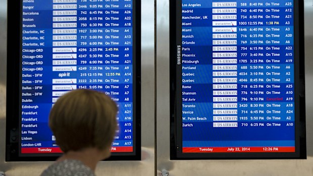 A woman passes by a departure board at the Philadelphia International Airport that shows that US Airways Flight 796 to Tel Aviv has been canceled. (AAP)