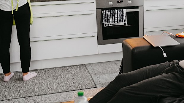 Woman in the kitchen while man sits on lounge