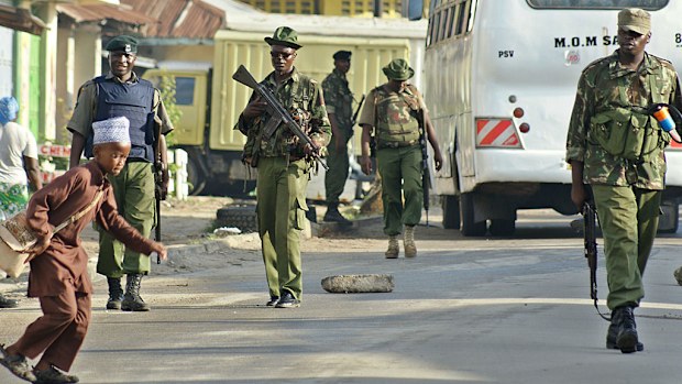 A Muslim schoolboy runs across a road past police officers patrolling around the Masjid Swafaa mosque in Mombasa, Kenya. (Getty Images)