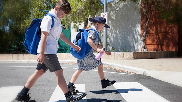 School children crossing the road safely at the cross walk. 