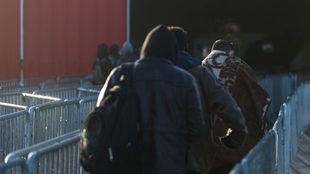 Minor migrants walk the closures towards the registration center in the jungle of Calais in Calais, France, on 25 October 2016. (AFP)