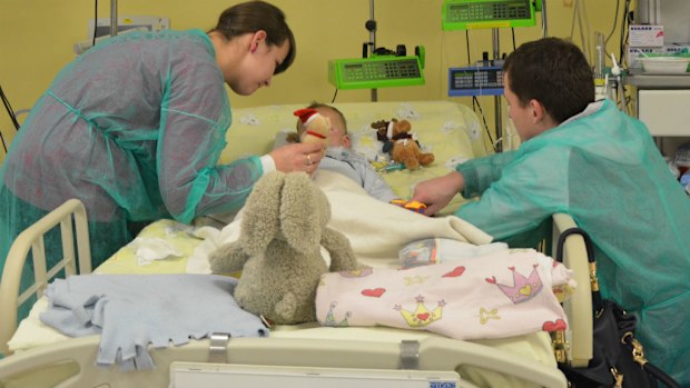 Two-year-old Adam is seen with his mother Paulina, his father Mateusz and a teddy bear in a Krakow hospital. (AAP)