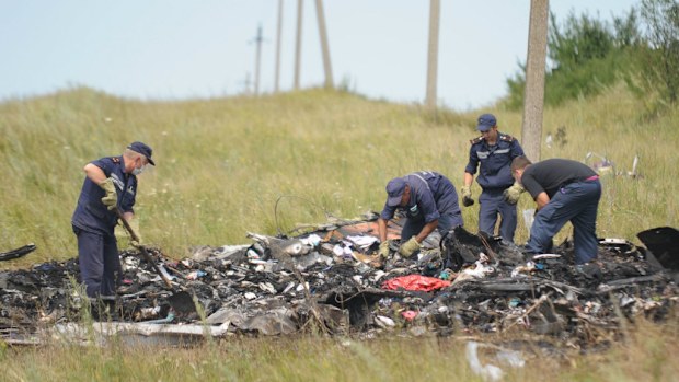 Search and rescue specialists inspect the crash area of MH17. (Getty)
