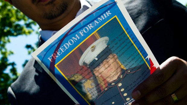 A man reads a flyer with a photo of US Marine Amir Hekmati on May 19 during a vigil held in Lafayette Park across from the White House in Washington. He has been imprisoned in Iran on espionage charges. His mother pleaded for President Barack Obama to seek his release.