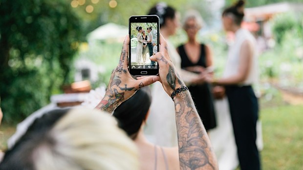 Guest taking wedding photo on phone 
