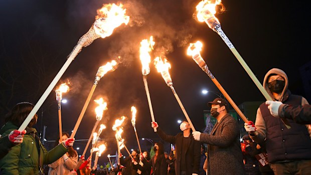 Protesters carry torches as they march toward the presidential Blue House during a rally against South Korea's President Park Geun-Hye in central Seoul on December 3, 2016. (AFP)