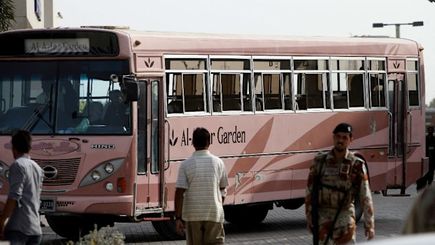 Pakistani paramilitary trioop stands guard near a bus targeted by gunmen in Karachi. (AAP)
