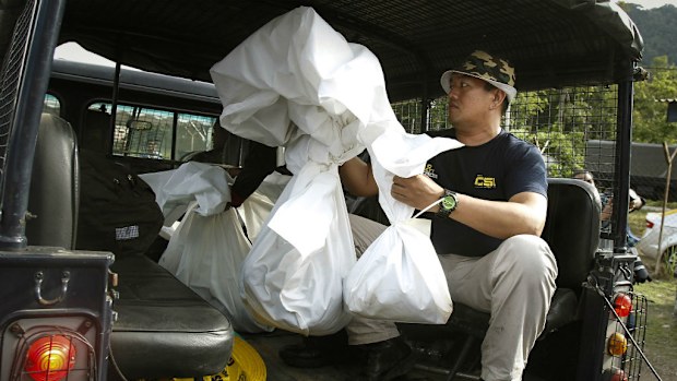 A Malaysian Forensic team personnel carries bags of human remains. (AAP)