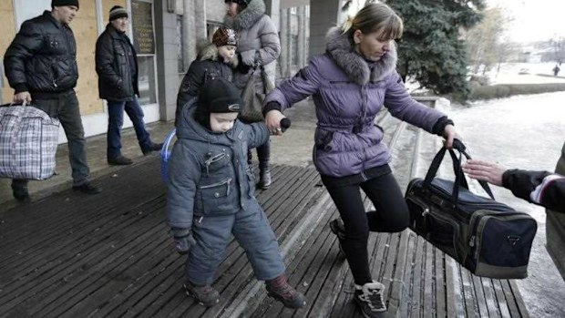 People carry their belongings to a bus to leave the town of Debaltseve, Ukraine, as fighting intensifies. (AP)