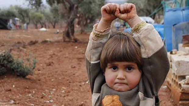 Four-year-old Syrian boy Adi Hudea poses, arms raised in surrender, after mistaking a camera for a gun. (Osman Sağırlı/Twitter/Nadia Abu Shaban)