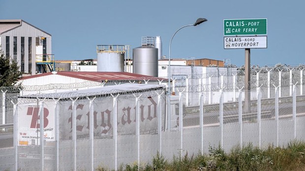 A lorry drives along a protection fence, preventing access to a circular road leading to the port of Calais, next to the "Jungle" migrant camp, in Calais, northern France, on September 8, 2016. (AFP)
