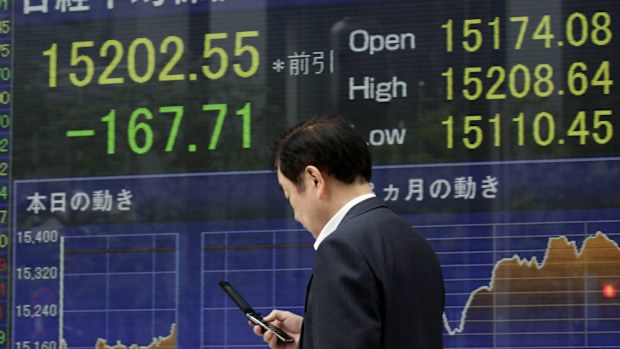 A Tokyo businessman walks past a stock market display showing the dramatic fall of the nikkei in reaction to the MH17 tragedy. (AAP)