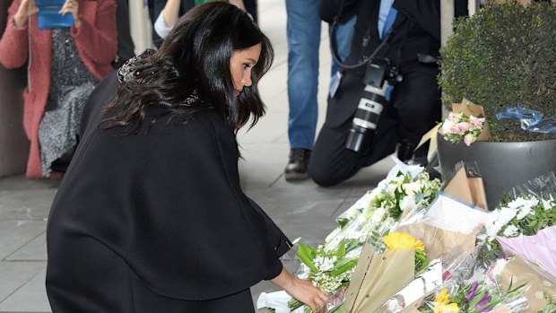 The Duchess places a bouquet of flowers, adding to the floral tribute.