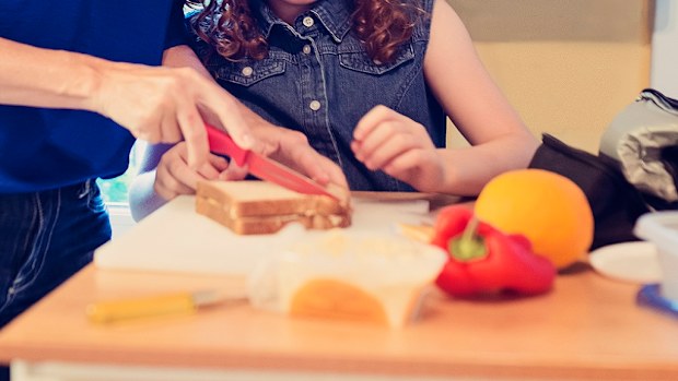 Mother and daughter cutting sandwich.