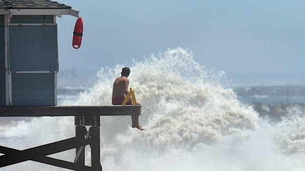 A lifeguard keeps a lookout as big waves, caused by hurricane Marie, crash ashore at Seal Beach, California. (Getty)