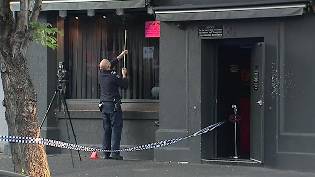 Police examine a section of the strip club frontage that was shot. (9NEWS)