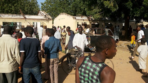 People inspect the damaged school buildings after a blast in northern Nigeria killed at least 47 students. (AAP)