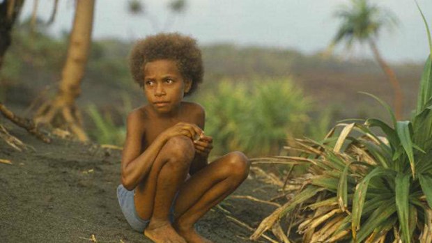 A Ni Vanuatu child sitting on volcanic sand. (AAP)