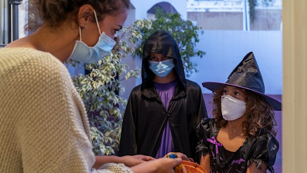 Children dressed in halloween costumes Trick-Or-Treating. They wear face masks. Covid-19 times. New normal concept.