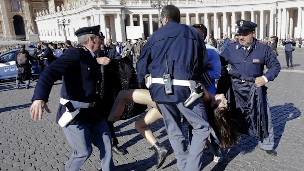 Vatican police grapple with one of the topless Femen protesters in St Peter's Square. (AAP)