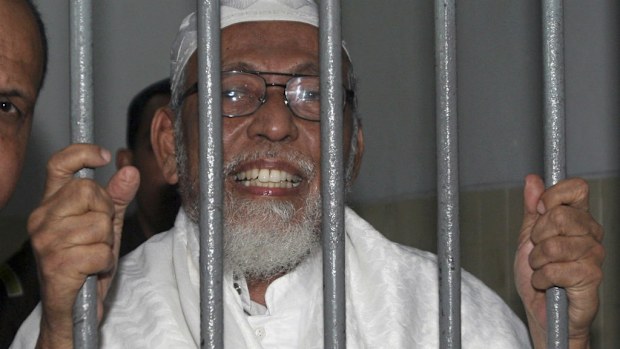 Radical cleric Abu Bakar Bashir talks to reporters from behind bars of a holding cell in 2011.