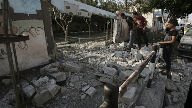 Palestinians inspect the destroyed wall of a hospital in Gaza. The Israeli military has claimed the hospital was attacked by Hamas. (AAP)