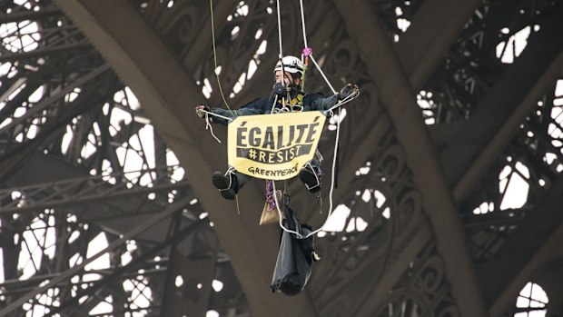 A Greenpeace activist hangs from a cord after unveiling a banner reading liberty, equality, fraternity on the Eiffel Tower in Paris early on May 5, 2017. (AFP)