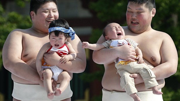 The wrestlers attempt to bring the babies to tears. (AAP)