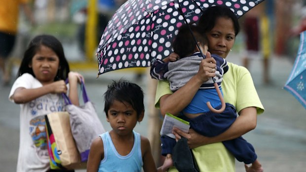  Filipino mother carries her child during a downpour on their way to an evacuation centre. (AAP)