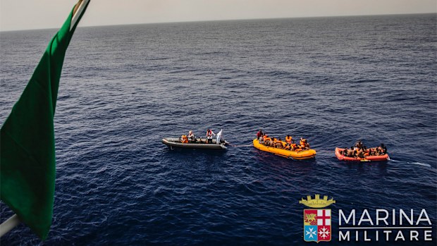 Rescuers tow migrants to the Italian Navy ship Vega, after the boat they were aboard sunk. (AAP)