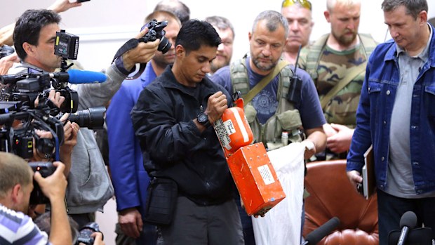  Malaysian expert (C) checks one of the two black boxes of the crashed Malaysian Air airliner flight MH17 after they were handed over by separatists to a Malaysian delegation, during a press conference organized in Donestk. (AAP)