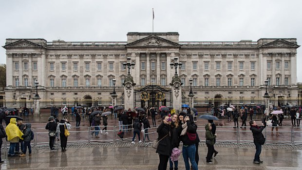 Tourists take photographs in front of Buckingham Palace in London on November 12. (AFP)
