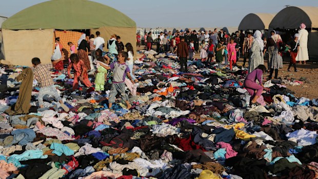 Members of the Yazidi community claim clothes delivered by a charity to a refugee camp. (AAP)
