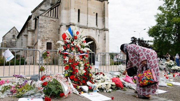 Muslims put flowers and hold a minute of silence on July 29, 2016 in front of the church if Saint-Etienne-du-Rouvray, western France, where French priest Jacques Hamel was killed on July 26 during a hostage-taking attack claimed by ISIL. (AFP)