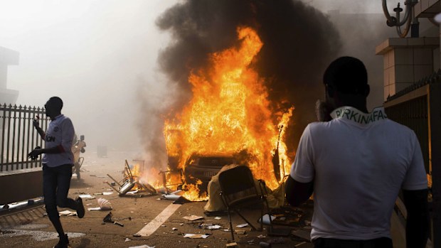 A car burns outside the parliament building in Burkina Faso. (AAP)