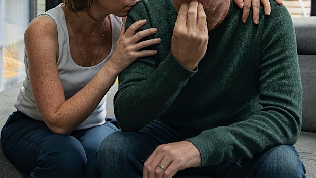 Sad couple sitting on bed.