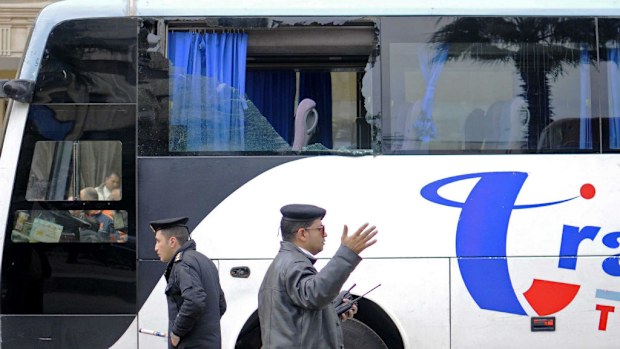  Egyptian police officers stand next to a bus with damaged windows. (AAP)