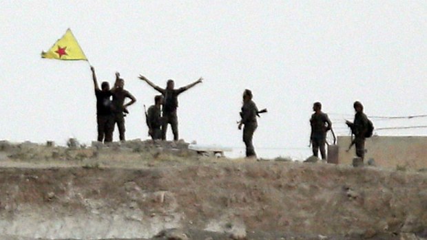 Kurdish fighters with the Kurdish People's Protection Units, or YPG, wave their yellow triangular flag in the outskirts of Tal Abyad. (AAP)