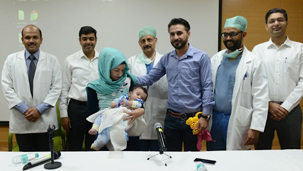 Iraqi parents Gufran Ali (3L) and Sarwed Ahmed Nadar (3R) pose with their eight month old son Karam (C) and physicians. (AFP)