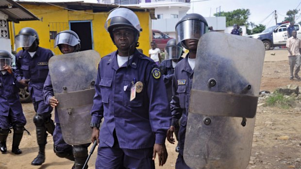Liberia policemen, dressed in riot gear disperse a crowd blocking a main road, as they watch health workers deal with the body of a man suspected of dying from the Ebola virus, in the city of Monrovia, Liberia. Picture: AP