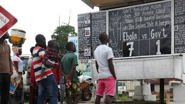 Liberians read the Daily Talk chalk board on the Ebola outbreak situation in the capital Monrovia, Liberia. (EPA/AHMED JALLANZO)