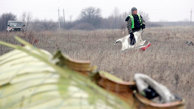 A Dutch expert holds a piece of the wreckage of Malaysia Airlines passenger jet MH17 at the crash site in rebel-held Grabovo village. (AAP)